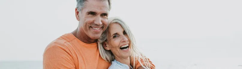 Casal de idosos a sorrir abraçados na praia — Consultas