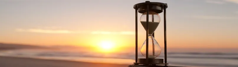 Um relógio de areia ao pôr do sol na praia — Consultas