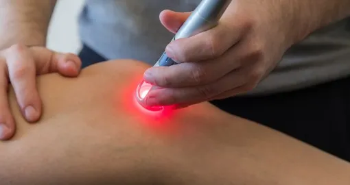 Mão aplica dispositivo com luz vermelha na pele — Medicina Laser