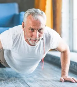 Homem idoso a fazer flexões com auscultadores — Exercício físico na prevenção e tratamento de doenças