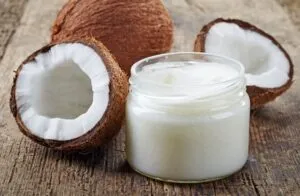 Vidro com creme branco junto a coco partido e inteiro sobre madeira — Ómega 3 e outras gorduras saudáveis