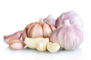 Cabeças de alho inteiras e dentes descascados sobre fundo branco — 10 alimentos que melhoram a saúde e a potência