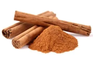 Varetas de canela e pó de canela sobre fundo branco — 10 alimentos que melhoram a saúde e a potência