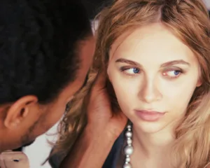 Mulher de olhos azuis com colar de pérolas ao lado de homem de cabelo escuro — Gestos que falam – os sinais escondidos