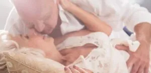 Casal idoso deitado na cama, abraçados e a sorrir — O ciclo sexual do homem