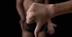 Mão com gesto de polegar para baixo, fundo escuro — A impotência tem cura?