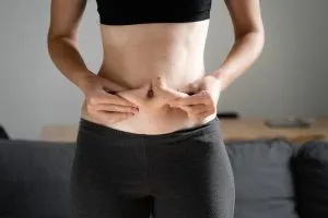 Pessoa a segurar a barriga com as mãos — Os benefícios de uma máquina de remar